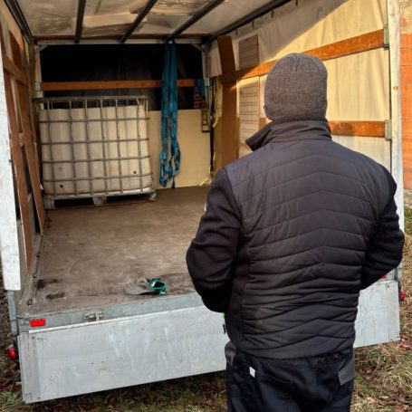 Erledigter Auftrag Ein Mann steht vor einem leeren Transporter, der eine Holzverkleidung hat.